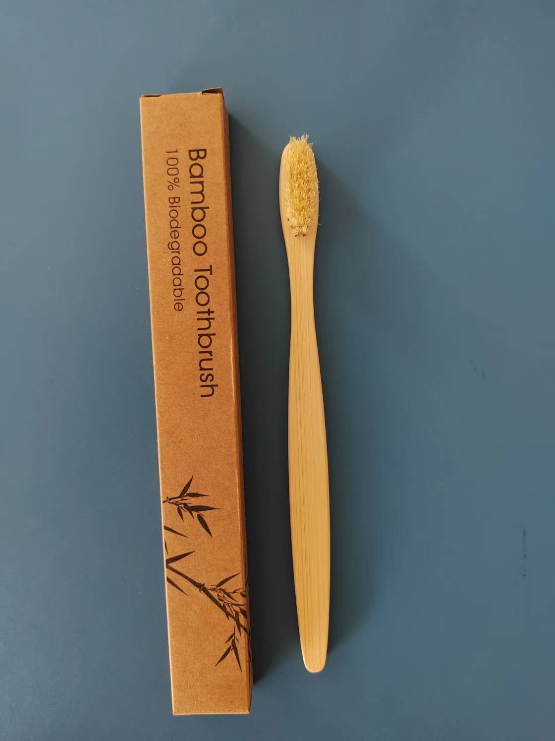 Flat-handle bamboo toothbrush with light natural boar bristles, shown beside its single box